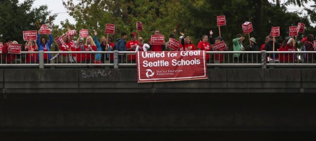 A group holds signs along a Northgate I-5 overpass in Seattle, as school district administrators and members of the Seattle Education Association (SEA) meet Thurs., Aug., 20 2015, for final contract negotiations, prior to the SEAâ€™s general membership meeting set for Monday.